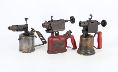 three antique cast iron tools are lined up on a white surface