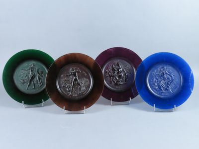 four different colored plates with different designs on them on a white surface