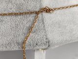 a close up of a gold chain on a white pillow