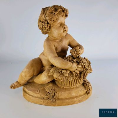 une statue ancienne représentant un garçon tenant un panier de raisins