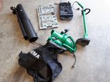 a green lawn mower sitting on the floor next to a black bag