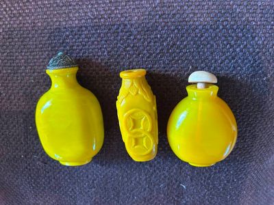 Trois vases jaunes sont posés les uns à côté des autres sur une table