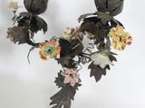 a black candle holder with flowers and leaves on it