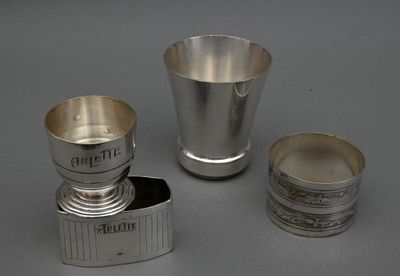 trois tasses en argent et un porte-tasse posés sur un plan de travail gris