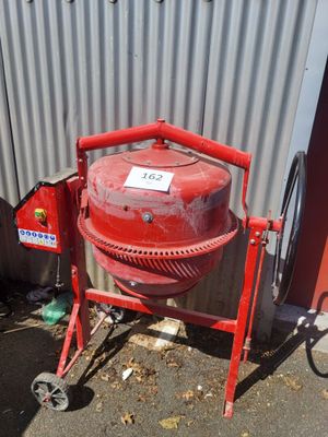 une bétonnière rouge garée devant un immeuble
