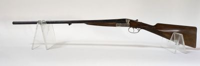 un fusil posé sur un socle transparent, devant un fond blanc