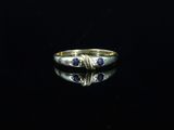 a gold ring with blue sapphires on a black surface