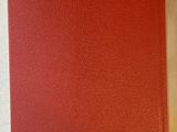 a red book sitting on top of a white table next to a cup of coffee