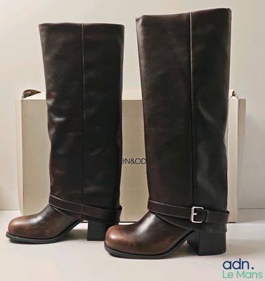 pair of brown boots sitting on top of a white table next to a box