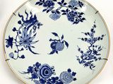 a blue and white plate with flowers and leaves on it