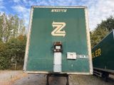 un grand camion-fourgon vert garé à côté d'une remorque verte