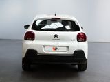 the rear of a white car is parked in a large room