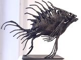 a metal sculpture of a fish on a pedestal