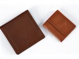 deux portefeuilles en cuir marron posés l'un à côté de l'autre sur une surface blanche