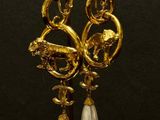 gold and pearl earrings on a stand with a black background