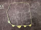 a close up of a gold necklace on a velvet surface
