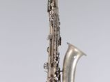 a silver saxophone sitting on top of a white surface