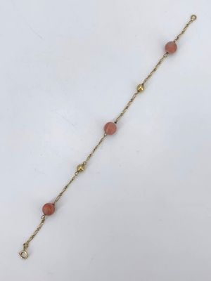 un bracelet plaqué or avec des perles roses et une chaîne en or