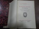 un livre ouvert posé sur une table en bois, à côté d'un livre rouge et noir