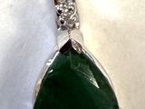 un gros plan d'un pendentif composé d'une pierre verte et d'un diamant, sur fond blanc