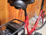 a red bike with a black seat next to a wooden wall