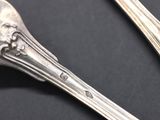two spoons and a fork on a black surface