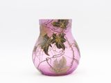 un vase en verre violet orné de feuilles, posé sur une surface blanche
