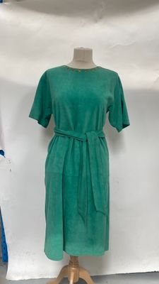 a green dress on a mannequin stand in front of a white backdrop