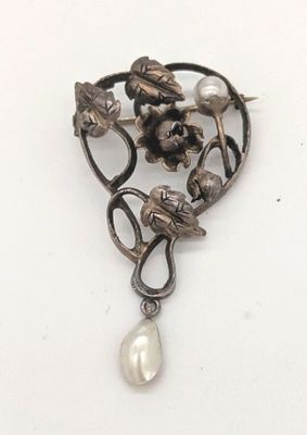 une image représentant une broche ornée de perles et de fleurs sur fond blanc