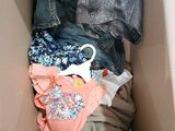 a cardboard box filled with clothes and a pair of scissors