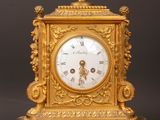 a gold clock sitting on top of a wooden table