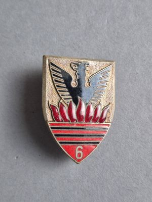un gros plan sur un insigne rouge et doré orné d'un oiseau