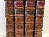 six vieux livres sont empilés sur une surface blanche