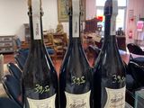 trois bouteilles de vin posées sur une table en verre dans une pièce