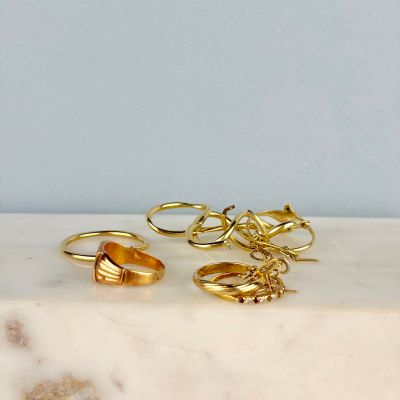 deux paires de bagues en or posées sur une dalle de marbre