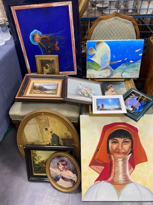 many pictures and paintings on a table in a room