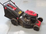 a red and black lawn mower sitting on the floor