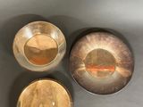 three metal bowls sitting on top of a table next to each other
