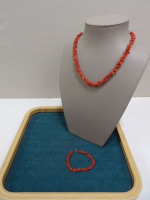 un collier et un bracelet en perles orange posés sur un plateau bleu
