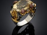 a close up of a ring with a yellow topaz and pink sapphires