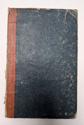 un vieux livre posé sur une surface blanche, orné d'une bande rouge