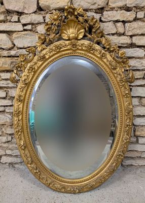 un miroir au cadre doré ouvragé accroché à un mur de pierre, avec un mur de pierre en arrière-plan