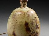 un vase marron et blanc sur lequel est posée une lampe