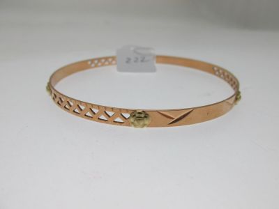 gros plan d'un bracelet en or sur une surface blanche