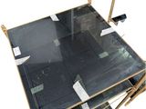 a glass top coffee table with a gold frame