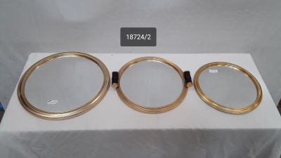 three round mirrors with gold rims on a white table