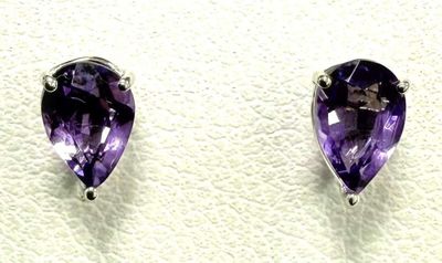 une paire de boucles d'oreilles en amethorate posées sur une surface blanche