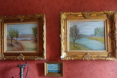 two paintings hanging on the wall next to a vase