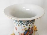 a white vase with a gold handle on a white plate