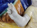 a figurine of a man sitting on a blue and yellow plate